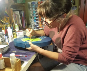 Amy bainting a bear claw on the lid of a large medicine box.